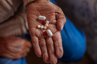 Detail of pills on the hand of an old man - ADSF09526