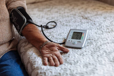 Älterer Mann, der seinen arteriellen Blutdruck mit einem Gerät kontrolliert - ADSF09530