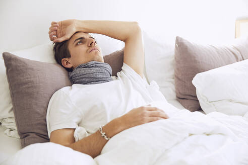 Sick thoughtful young man resting on bed at home - UKOF00016