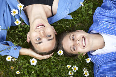 Close-up of cheerful young friends relaxing on grassy land in garden - UKOF00062