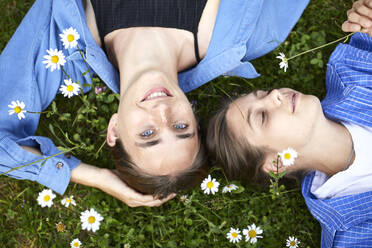 Close-up of female friends relaxing on grassy land in garden - UKOF00063