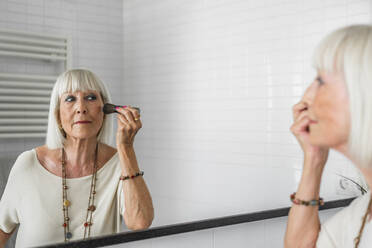 Ältere Frau trägt Make-up auf, während sie zu Hause in den Spiegel schaut - DLTSF01042