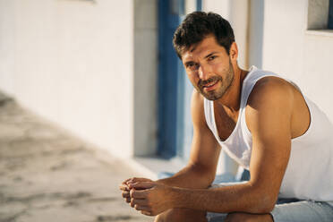 Close-up of handsome mid adult man sitting against wall during sunset - MPPF01006