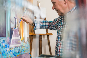 Aged man painting picture with brush - ADSF09593