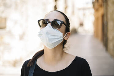 Portrait of woman with sunglasses and protective mask in city - XLGF00440