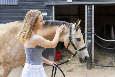 Young woman with horse on a farm - WPEF03248