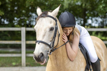 Young woman lying on the back of her horse - WPEF03254