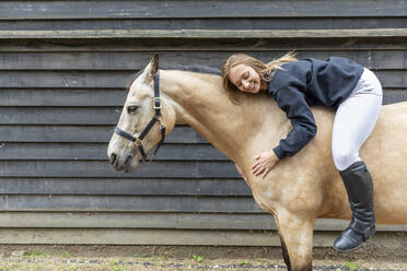Junge Frau auf dem Rücken ihres Pferdes liegend - WPEF03260