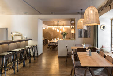 Stylish lamp shining over small tables and comfortable chairs in cozy restaurant - ADSF09639