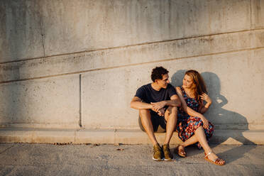 Man and woman looking at each other sitting at nearby street wall - ADSF09651