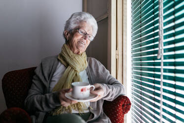 Ältere Frau mit einer Tasse Tee, die während der Quarantäne zu Hause bleibt - ADSF09696