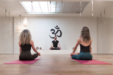 Rückenansicht von ausgeglichenen ruhigen Frauen und Mann sitzen auf Lotus-Pose mit Mudra nach auf Yoga-Klasse konzentriert - ADSF09710