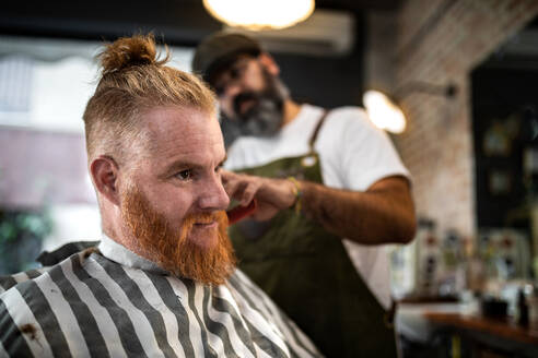 Moderne Friseur Barbier Schneiden eines erwachsenen Mannes Rothaarige Haare in Barbier Stuhl - ADSF09773