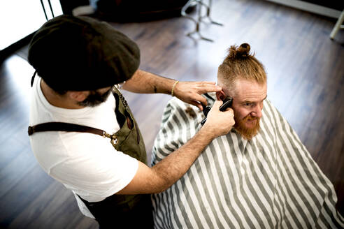 Von oben modernen Friseur Barbier Schneiden eines erwachsenen Mannes Rothaarige Haare in Barbier Stuhl - ADSF09775