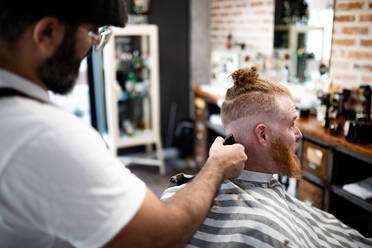 Seitenansicht modernen Friseur Barbier Schneiden eines erwachsenen Mannes Rothaarige Haare in Barbier Stuhl - ADSF09776