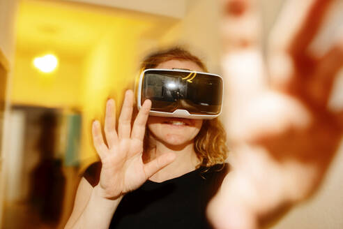 Nahaufnahme einer Frau, die durch einen Virtual-Reality-Simulator zu Hause gestikuliert - JATF01218