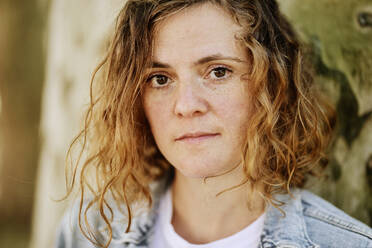 Close-up of serious mid adult woman with wavy hair in park - JATF01227