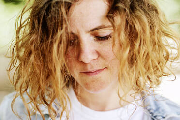 Close-up of thoughtful mid adult woman with wavy hair looking down - JATF01233