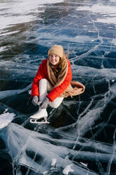 Frau sitzt auf gefrorenem Fluss und bindet die Schnürsenkel - ADSF09815