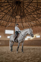 Rider riding dapple gray horse in round arena - ADSF09827