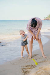 Fröhliches Kind, das mit seiner Mutter am Strand Spaß hat - ADSF09833