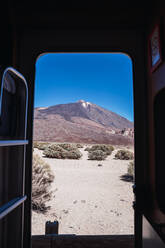Malerischer Blick aus dem Inneren eines Wohnwagens auf einen abgelegenen felsigen Berggipfel in einer malerischen Wüste, Spanien - ADSF09874