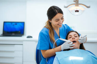 Zahnarzt und Assistentin untersuchen den Mund eines Patienten auf einem Stuhl mit Werkzeugen - ADSF09880