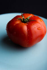 Hohe Winkel Nahaufnahme von reifen roten Tomaten auf Teller in der modernen Küche auf schwarzem Hintergrund platziert - ADSF09923