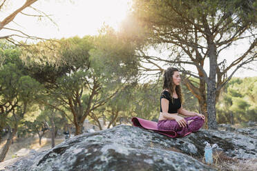 Yoga instructor meditating in forest - MRRF00251