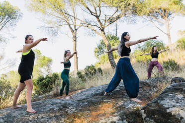 Yoga instructor exercising with women in forest - MRRF00256