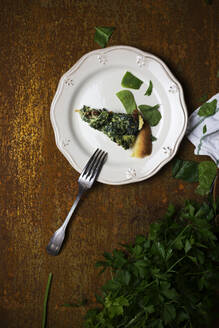 Oben eine Portion eines schmackhaften vegetarischen Gerichts mit frischer Petersilie auf einem Teller auf einer schäbigen Tischplatte - ADSF09943