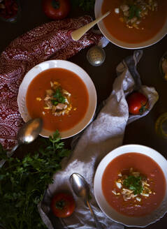 Von oben Schalen mit köstlicher Tomatensuppe mit Petersilie neben Servietten auf den Tisch gestellt - ADSF09974