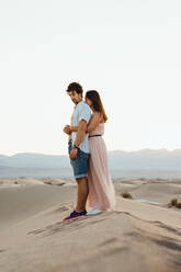 Side view of amorous lovely couple embracing touching hands in sandy hills of Death Valley - ADSF09981