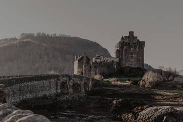 Stone castle with aged architecture with bridge near river on sunny day - ADSF10001