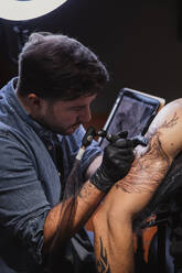 Master doing tattoo on forearm of male customer - ADSF10032