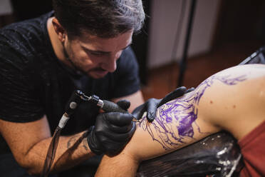 Master doing tattoo on forearm of male customer - ADSF10033