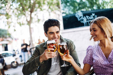 Fröhliches junges attraktives Paar genießt ein erfrischendes Getränk bei einem Spaziergang in der Stadt an einem warmen Tag - ADSF10091