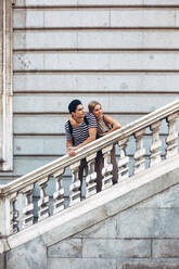 Attractive couple admiring view while standing on old stairs of historical building - ADSF10093