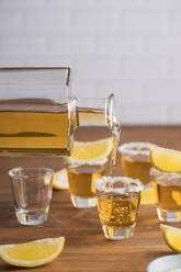 Von oben Gläser mit goldenem Tequila mit salzigem Rand und Zitronenscheiben auf einem Holztisch - ADSF10146