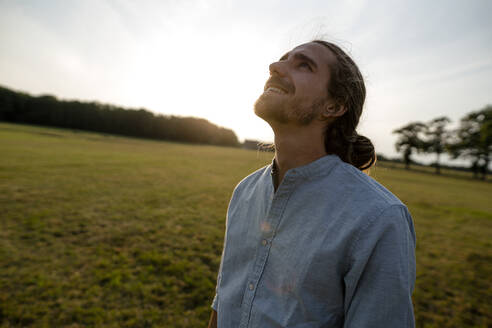 Content young man on a meadow in the countryside looking up - KNSF08296