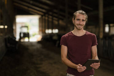 Porträt eines jungen Landwirts mit Tablet auf einem Bauernhof - KNSF08329