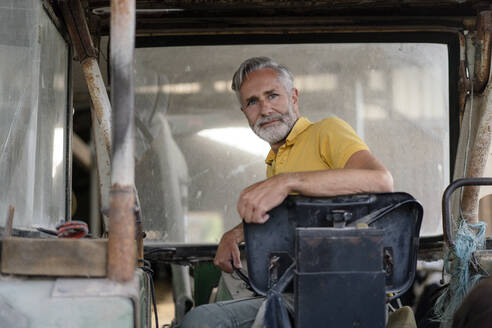 Porträt eines reifen Landwirts auf einem Traktor - KNSF08364