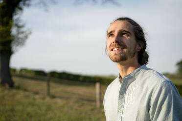 Content young man on a meadow in the countryside looking up - KNSF08379