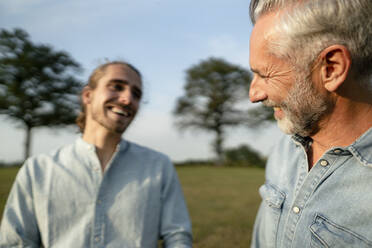 Happy father with adult son on a meadow in the countryside - KNSF08384