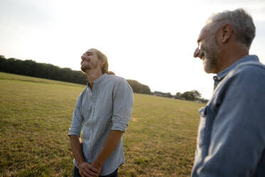 Happy father with adult son on a meadow in the countryside - KNSF08385