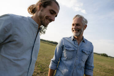 Happy father with adult son on a meadow in the countryside - KNSF08392