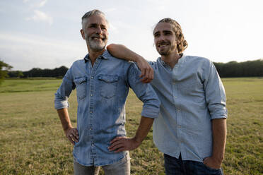 Happy father with adult son on a meadow in the countryside - KNSF08399