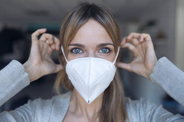 Portrait of young woman putting on protective mask - JSRF00983