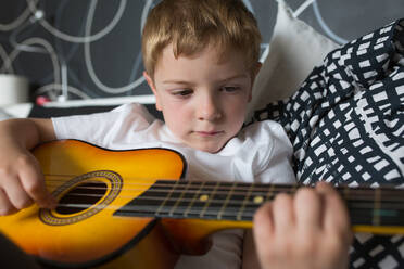 Young blonde boy playing toy guitar - ADSF10155