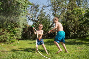 Kleine Kinder in Badekleidung, die herumrennen und sich gegenseitig mit Wasser aus dem Gartenschlauch bespritzen - ADSF10157